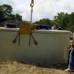 Lowering septic tank into hole